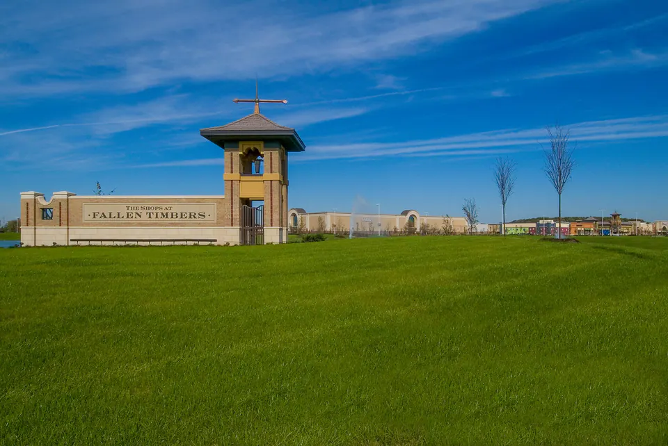 Fallen Timbers entry monument with tower, sign wall, open lawn, and blue sky